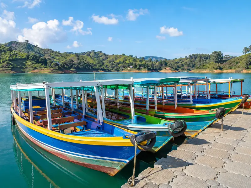 Colorful wooden tour boats moored at the Guatapé waterfront dock on the turquoise reservoir